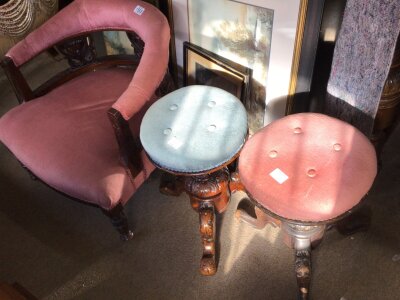 An Edwardian tub chair with pink upholstery and two music stools with adjustable circular seats on carved supports. (3)