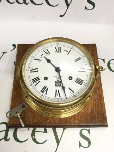 A vintage sewills brass ship clock with wooden mount.