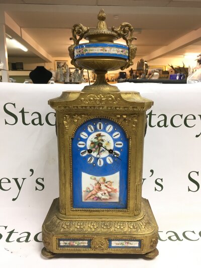 An antique french mantle clock with porcelain panel inlays painted in the sevres style.
