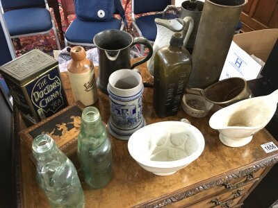A collection of items including glass bottles, a shell case, horse brass etc