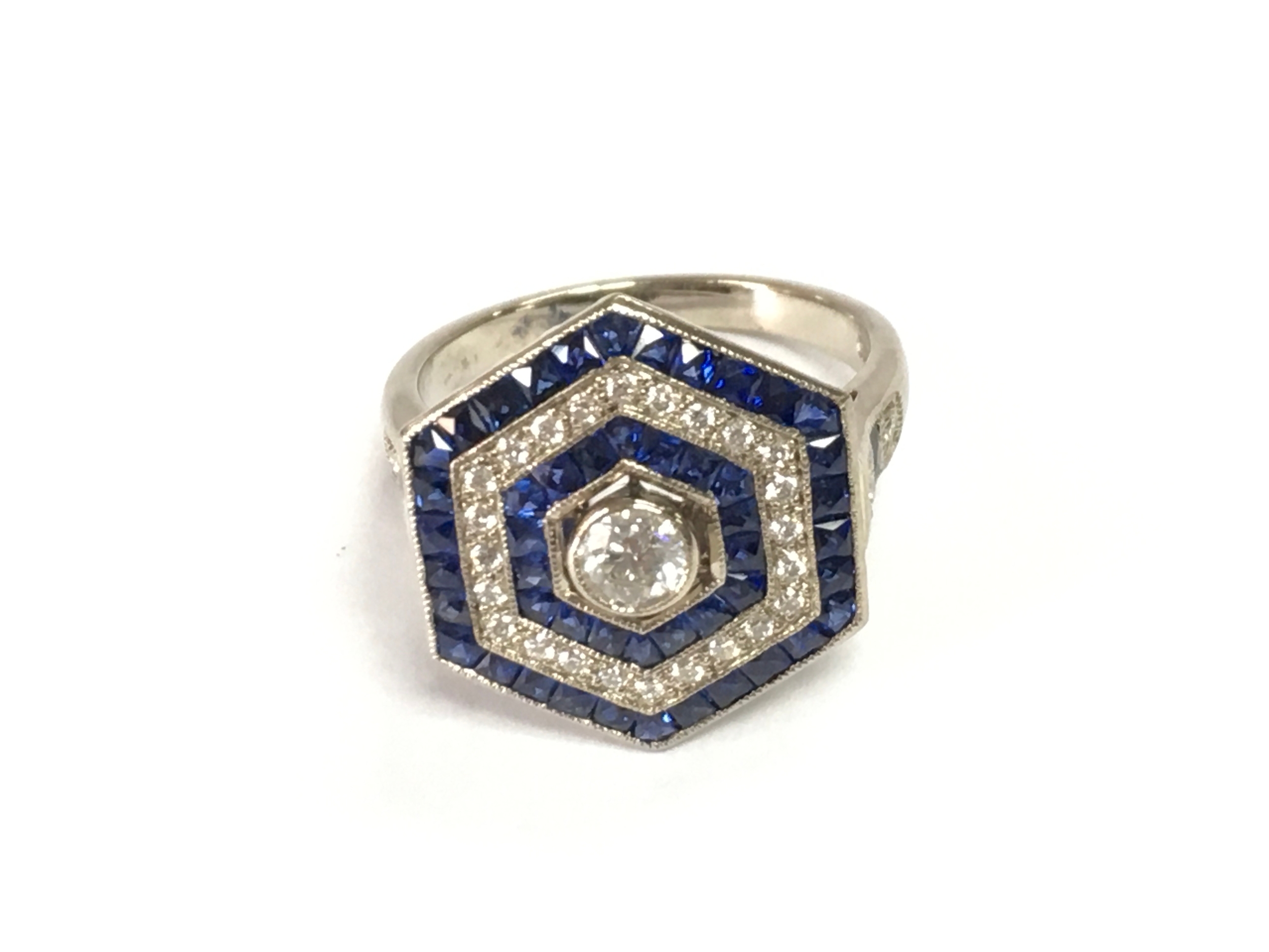 18ct white gold hexagonal ring set with diamonds and french cut sapphires. Approximately 0.58ct diamonds and 0.68ct sapphires. Size M