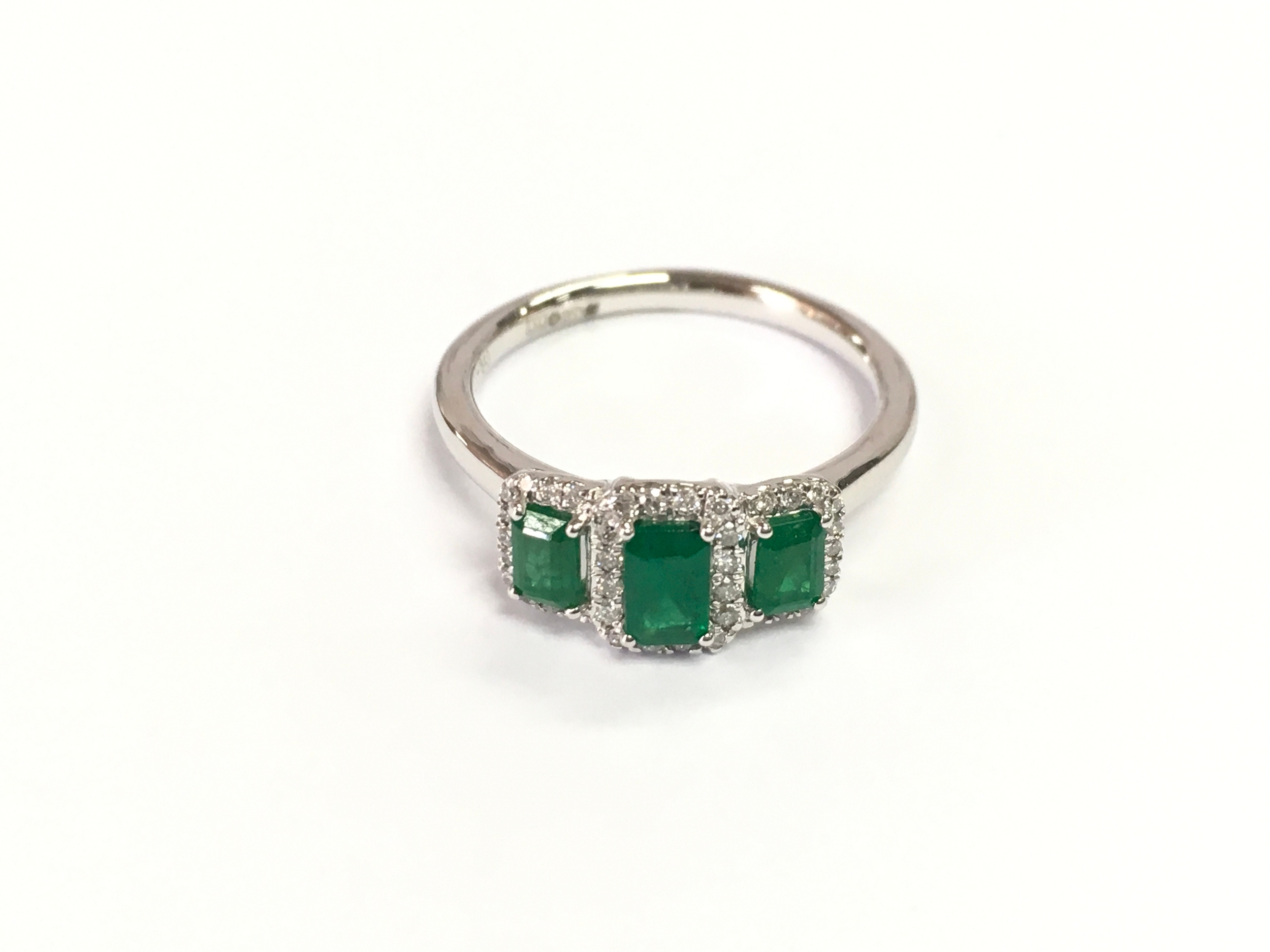 Platinum trilogy clsuter ring set with emerald and surrounded by diamonds. Size M