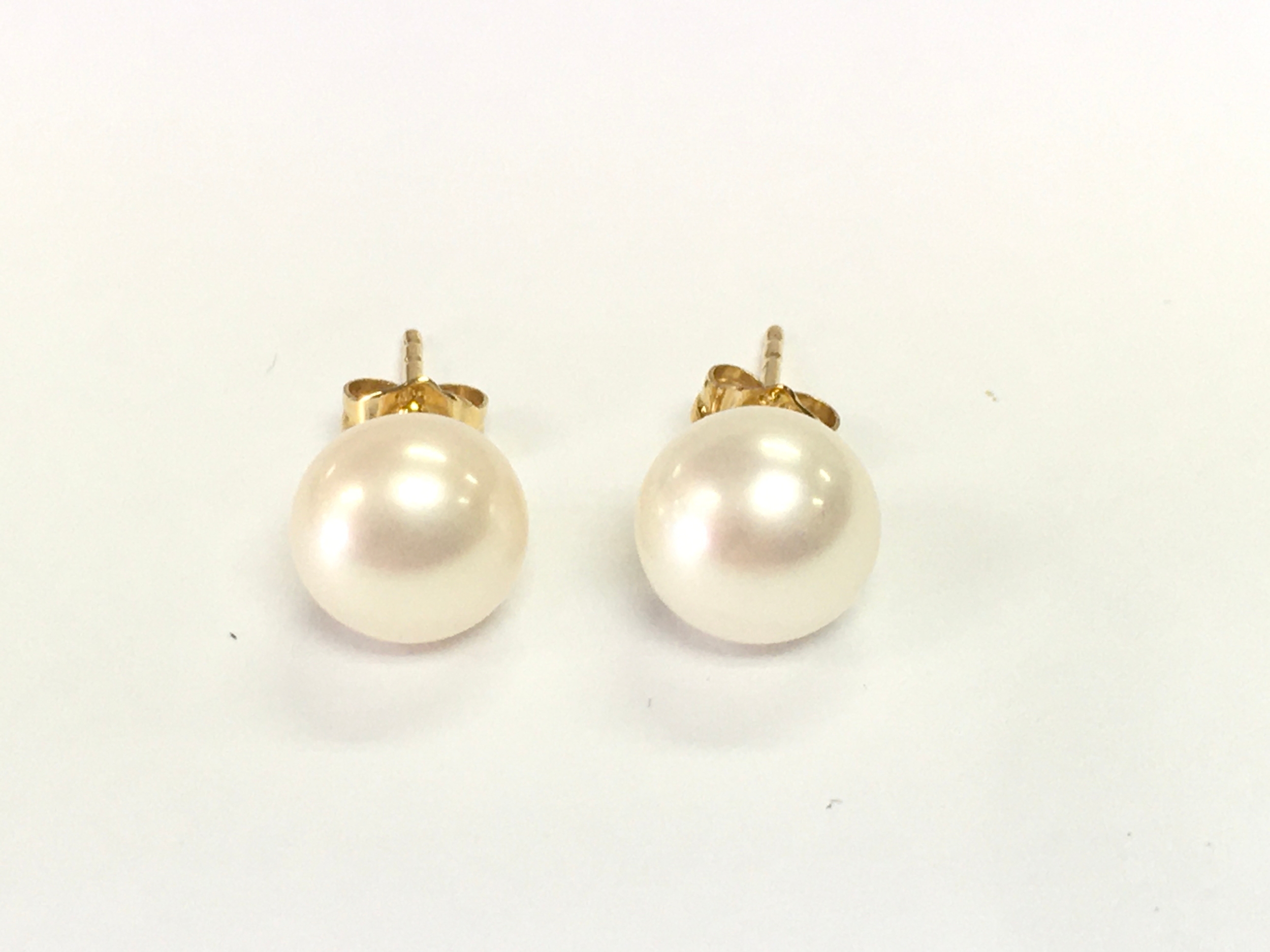 A pair of 9ct yellow studs set with white oblate spheroid cultured pearls.