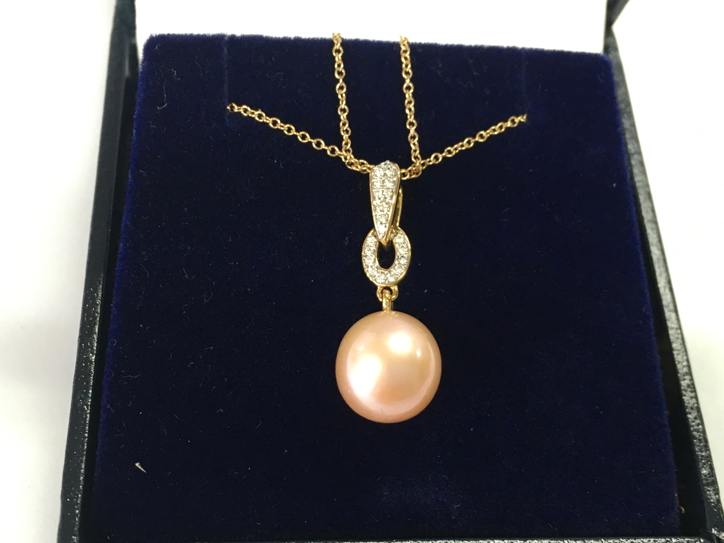 A 9ct gold pendant set with a pink / peach cultured pearl on a 9ct gold chain.