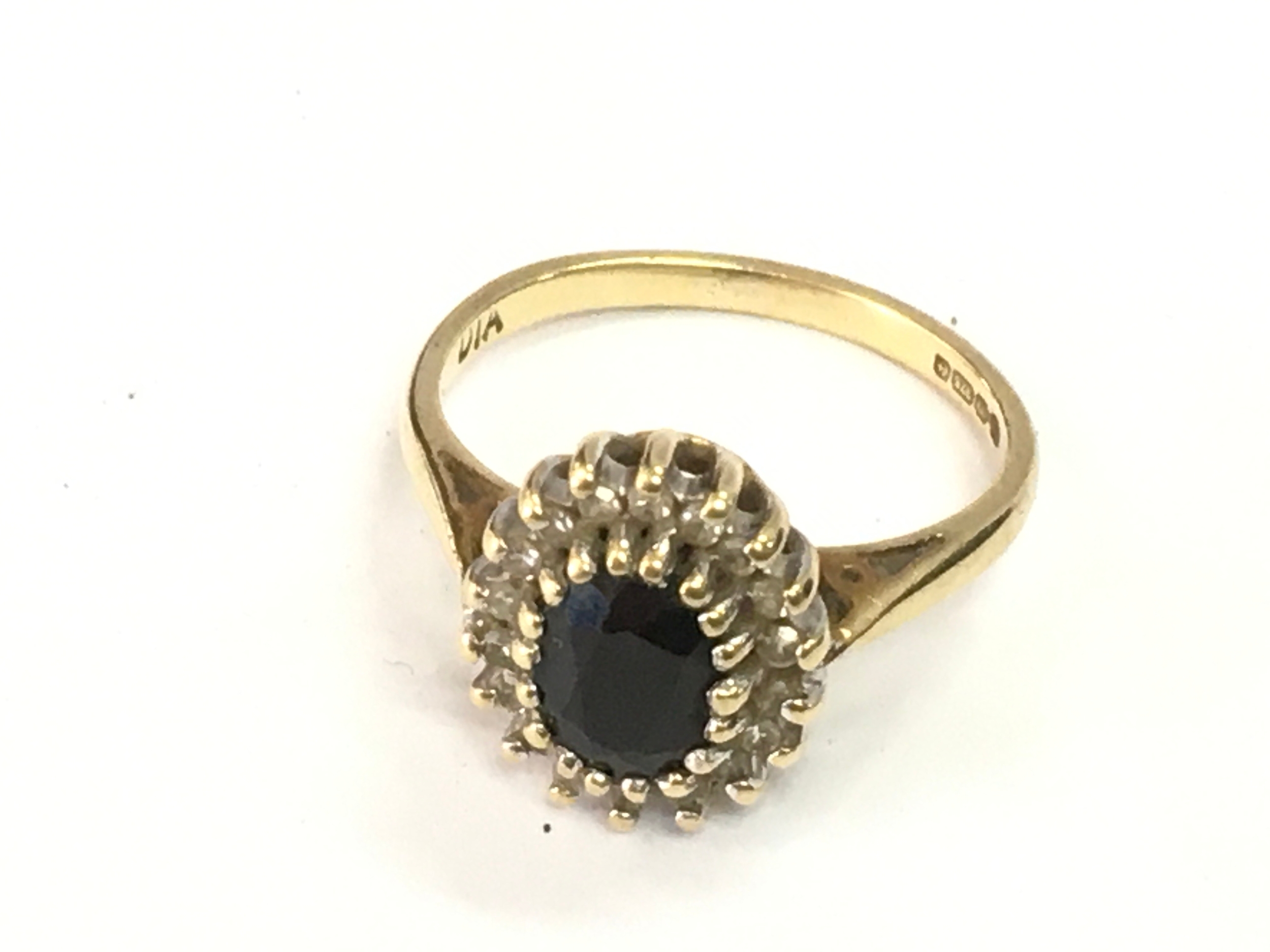 A 9ct gold ring with an old cut sapphire surrounded by small diamonds  , size H. 2.1g