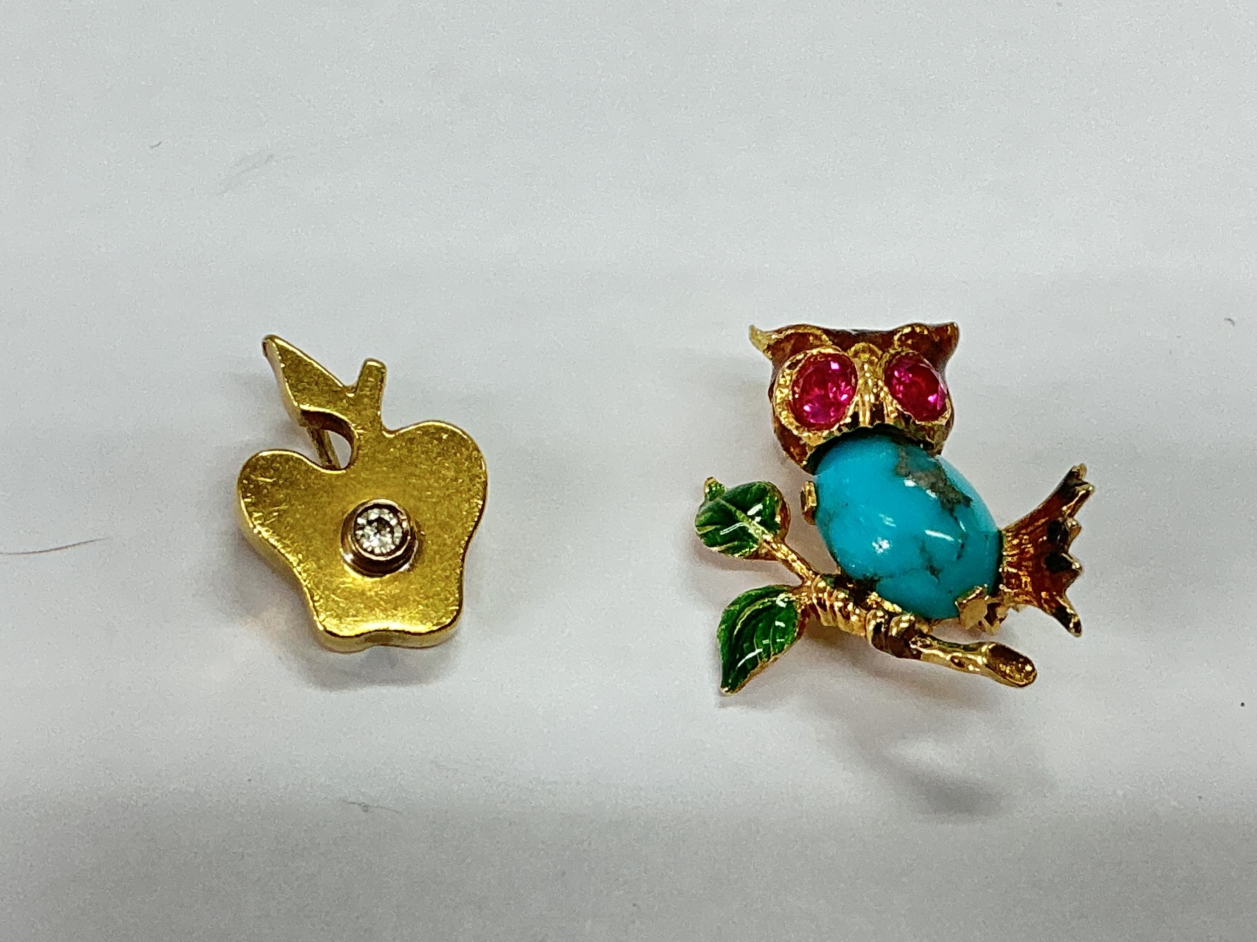 Two small gold brooches, one of an apple with a diamond chip plus one in the form of an owl set with gemstones, largest approx 2cm in length and approx total weight 7.9g.