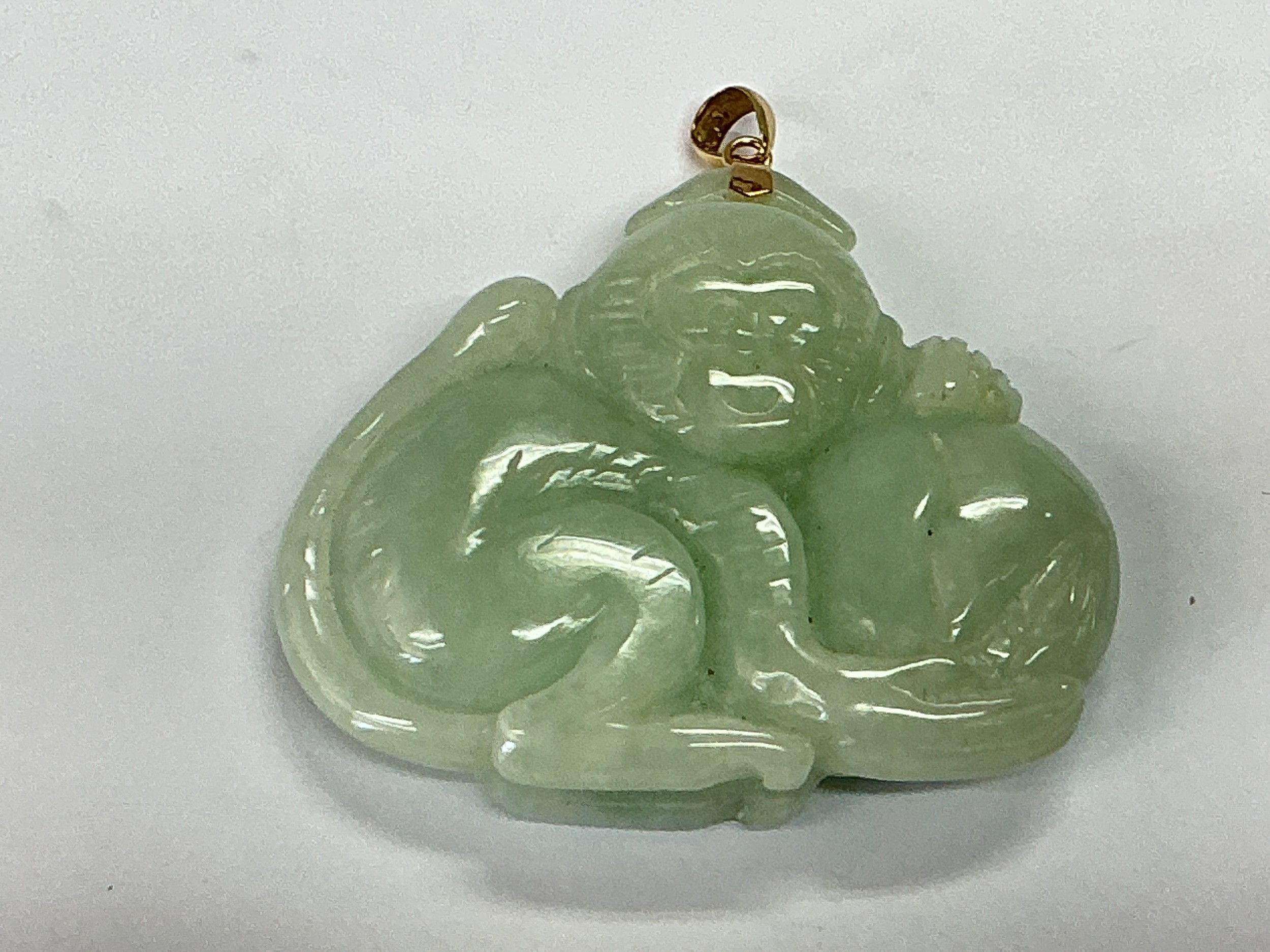 A jade and 14ct gold pendant in the form of a monkey, approx length 4.5cm.