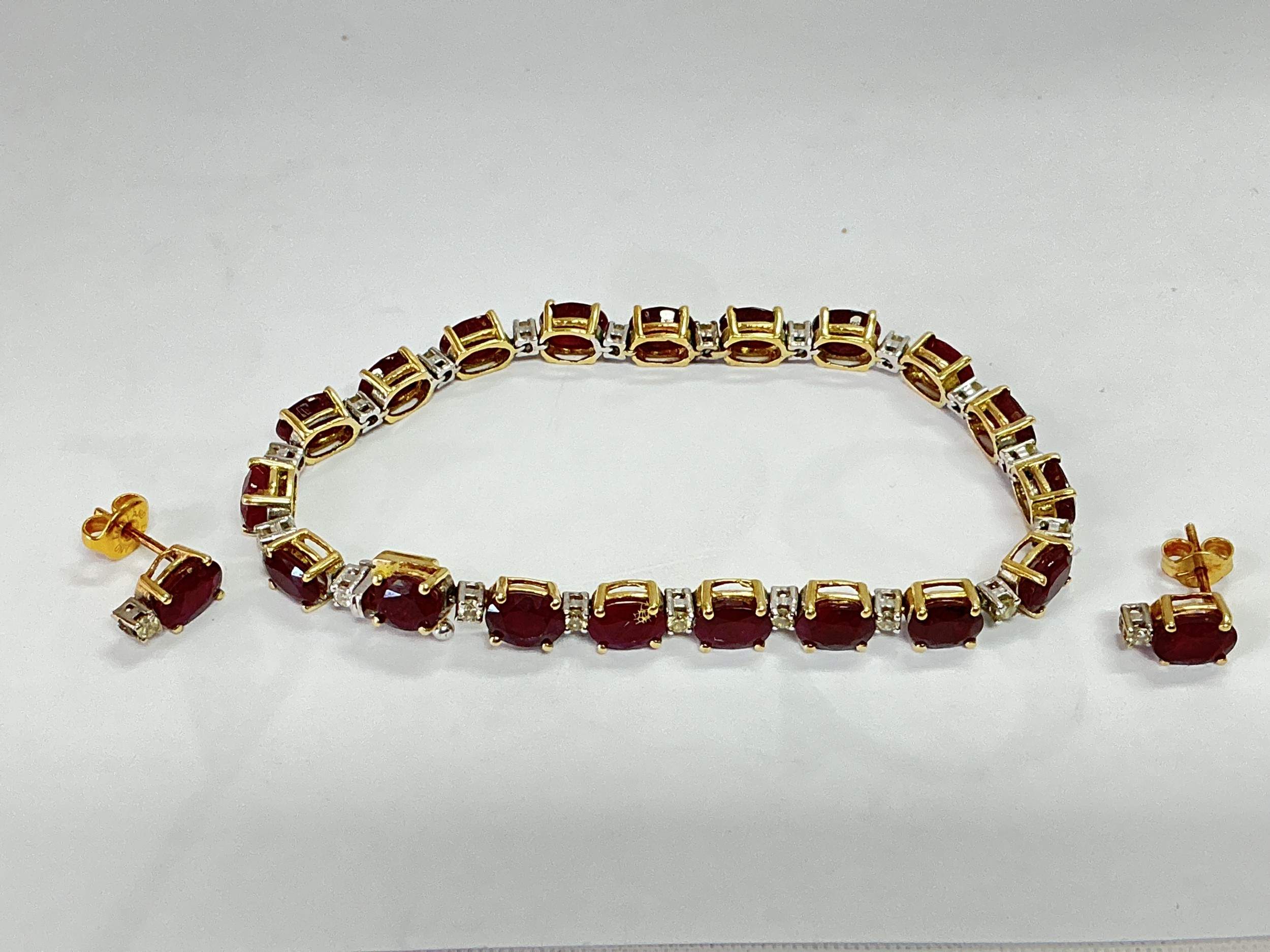 A diamond and ruby set tennis bracelet with a pair of matching earrings.