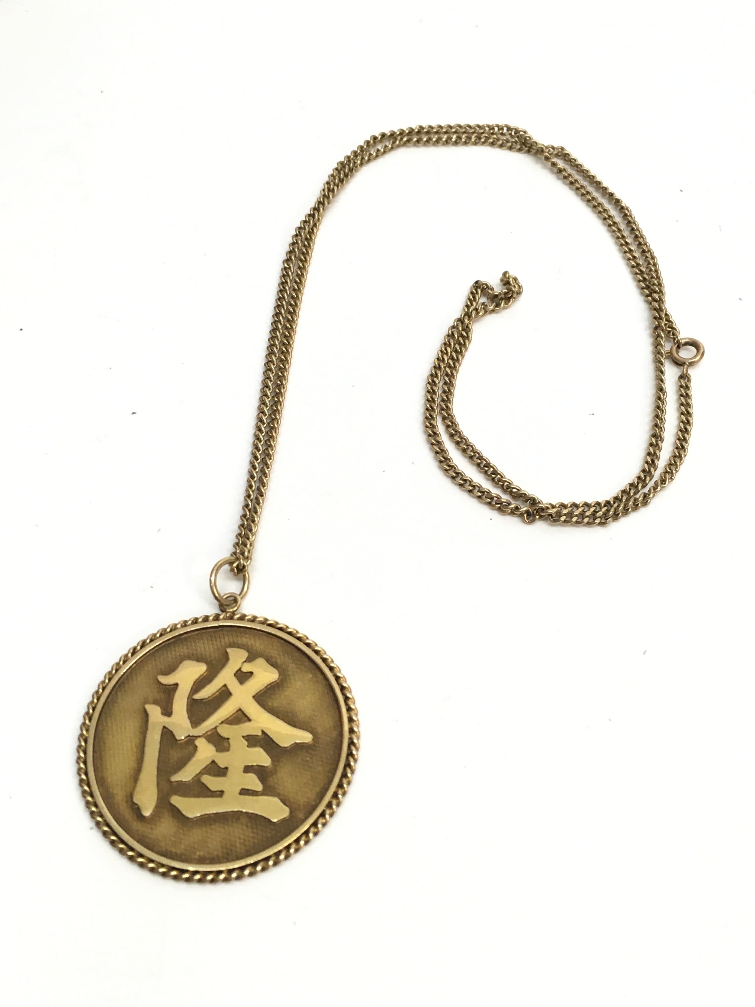 A 10k gold Chinese pendant on a 9ct gold chain (32cm long). 27.8g total weight 