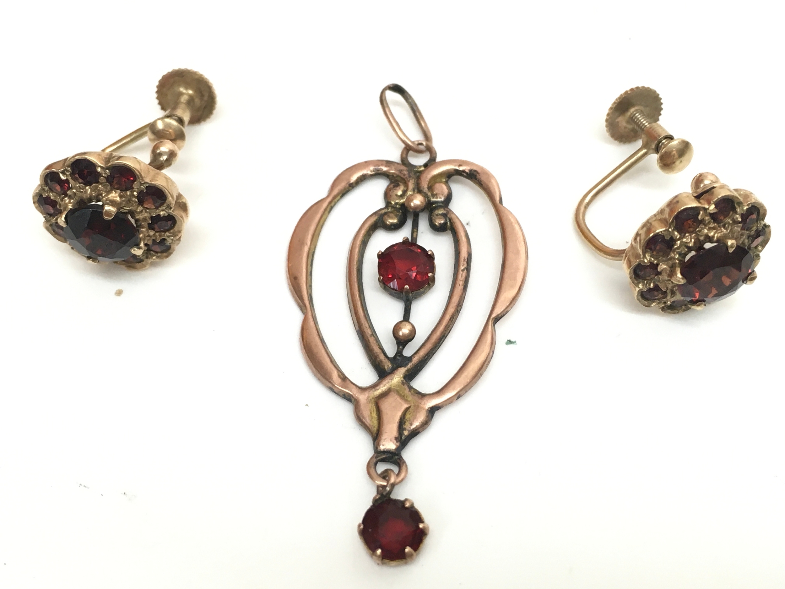 A 9ct rose gold red stone set pendant and 9ct gold red stone earrings.5.5g total weight