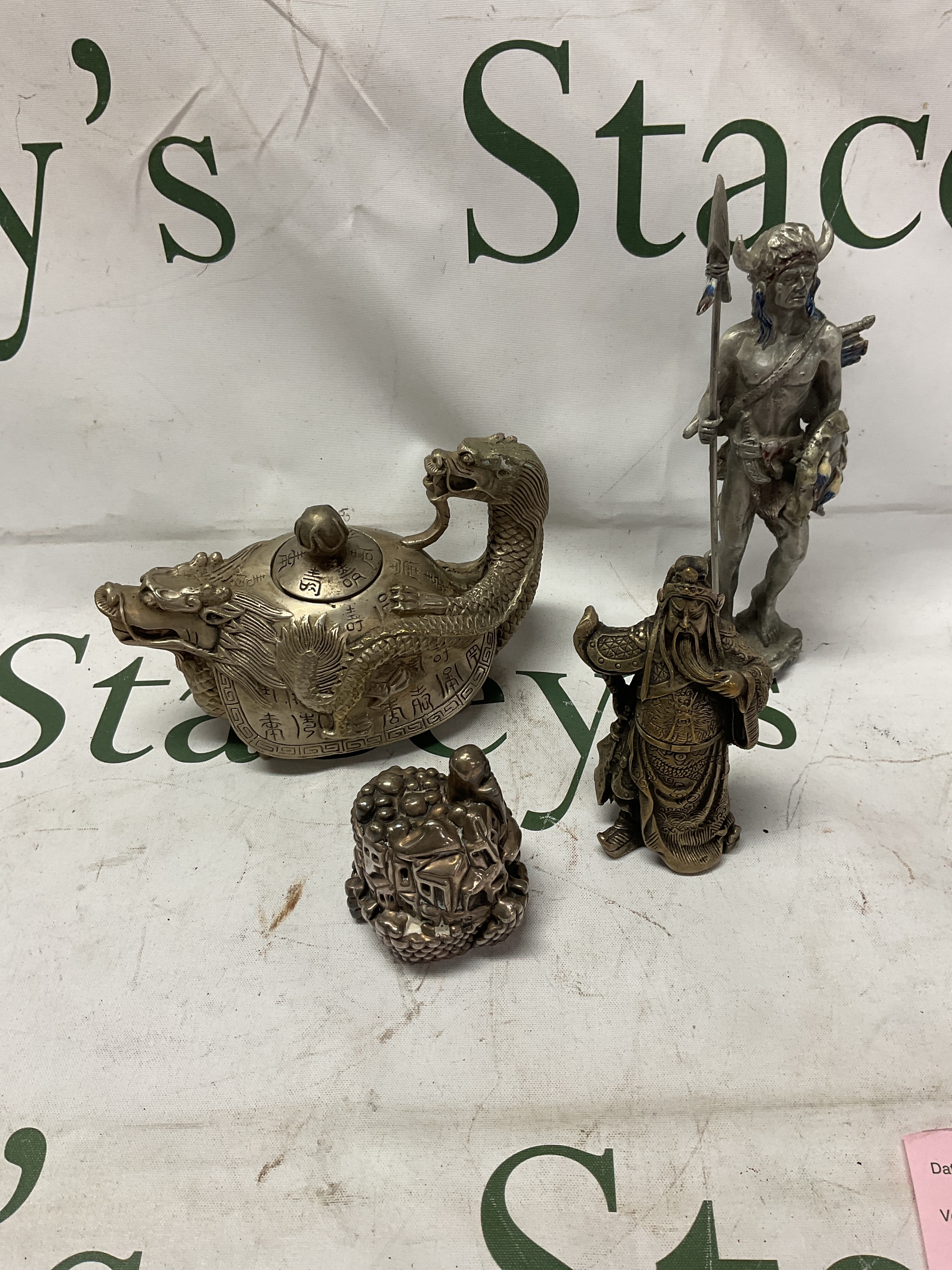 Silver covered figure of a hill scene along with Chinese and Native American warrior figures and a Chinese tea pot with dragon features.