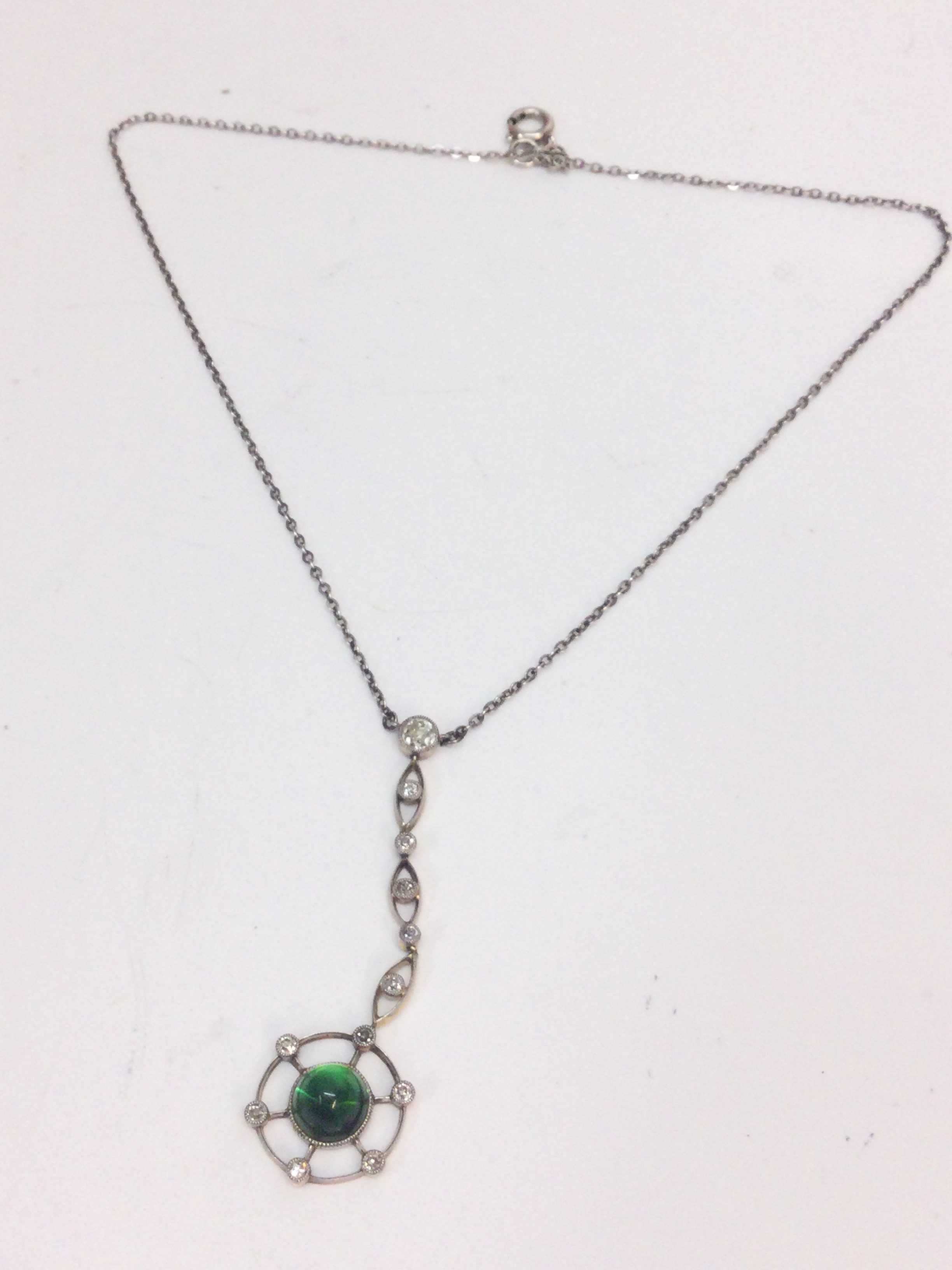 A gold Edwardian pendant set with diamond and chrysoberyl cabochon with a silver chain (18cm long). 5.1g total weight 