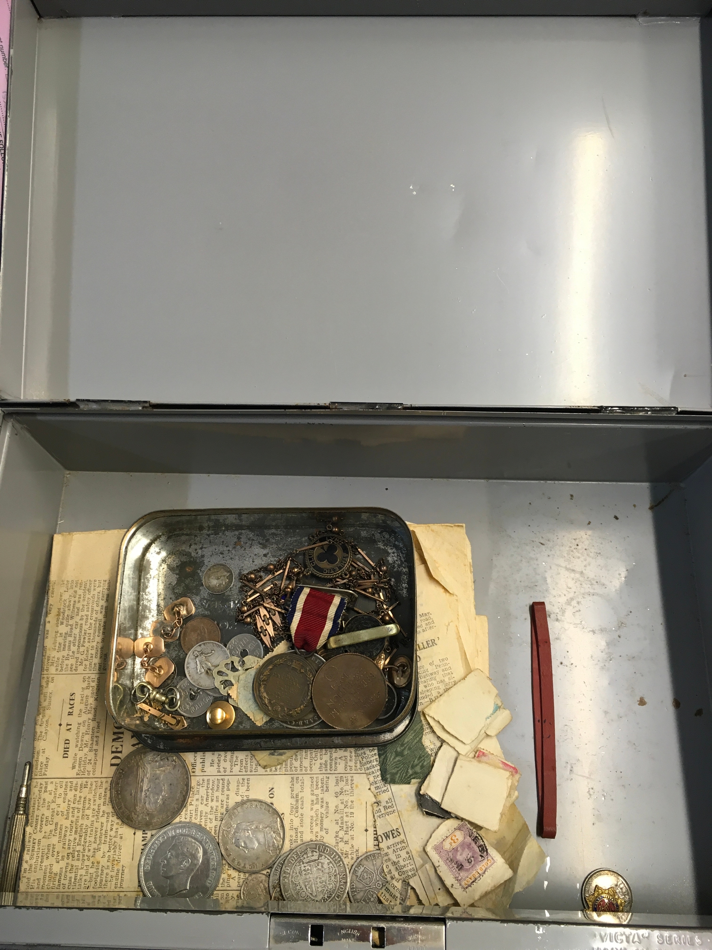 A tin containing ornaments, chains, coins, medals