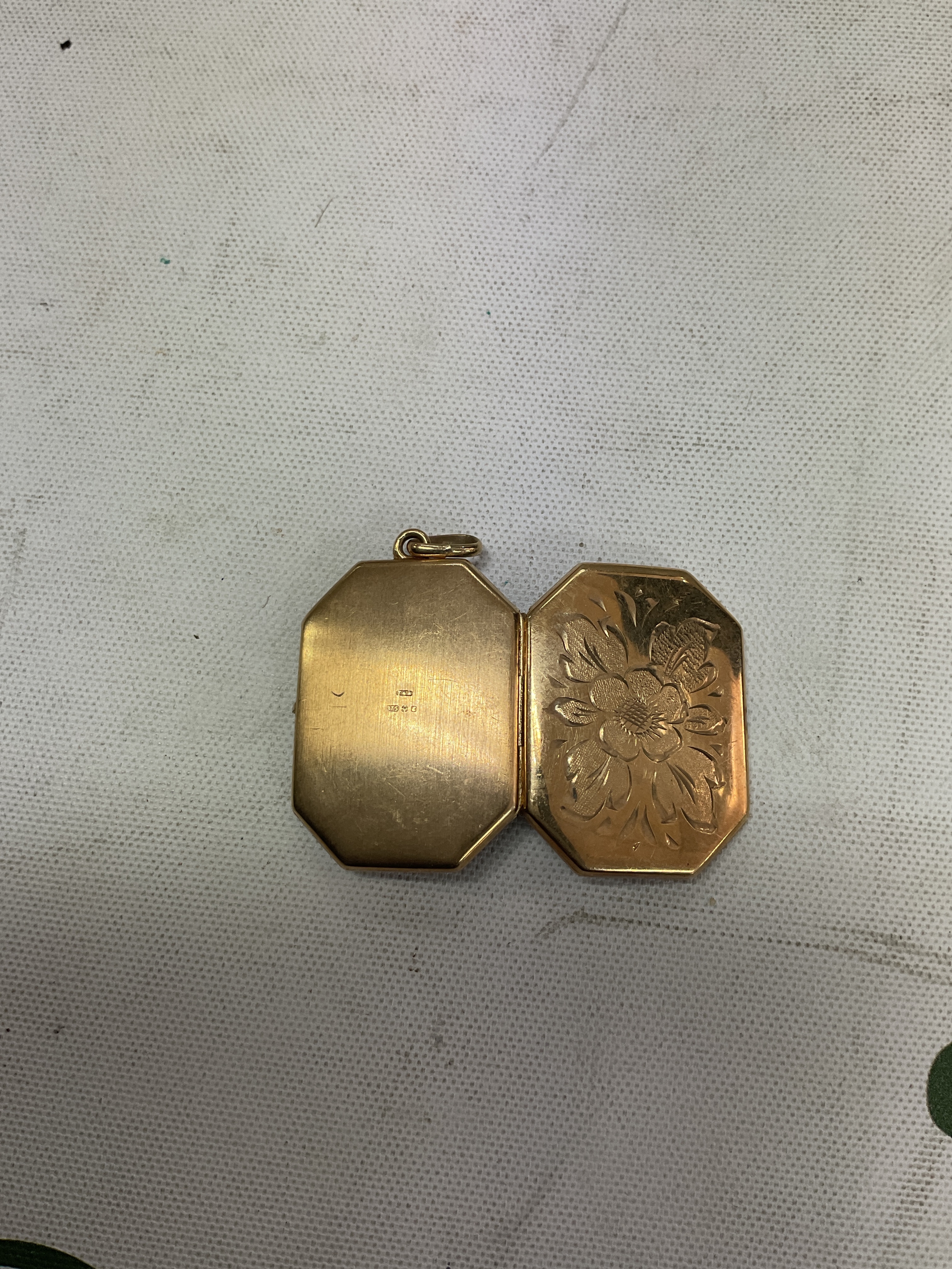 9ct octagonal locket with right cut floral decoration. Weight4.9 grams