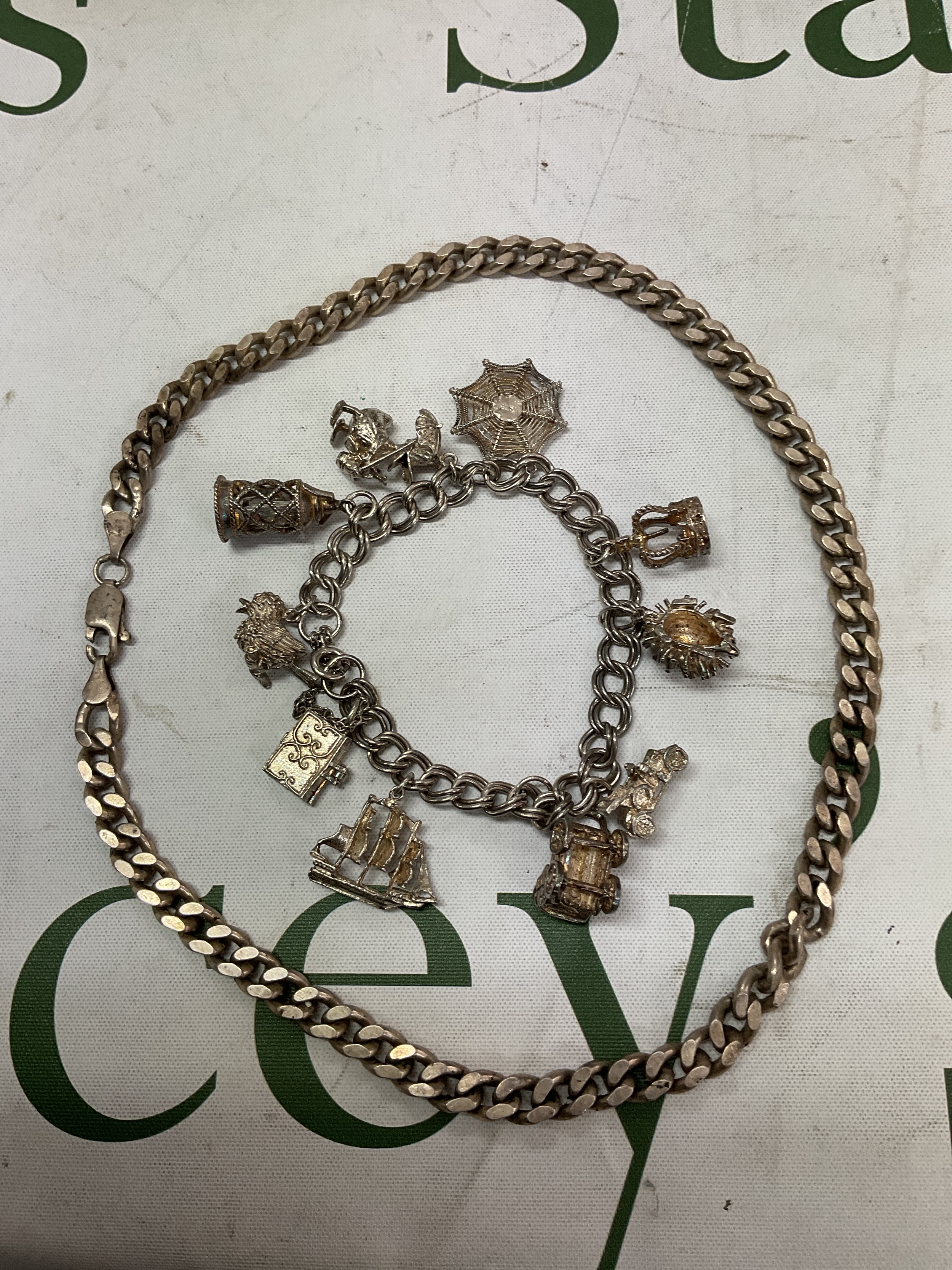 Heavy silver curb necklace and charm bracelet .