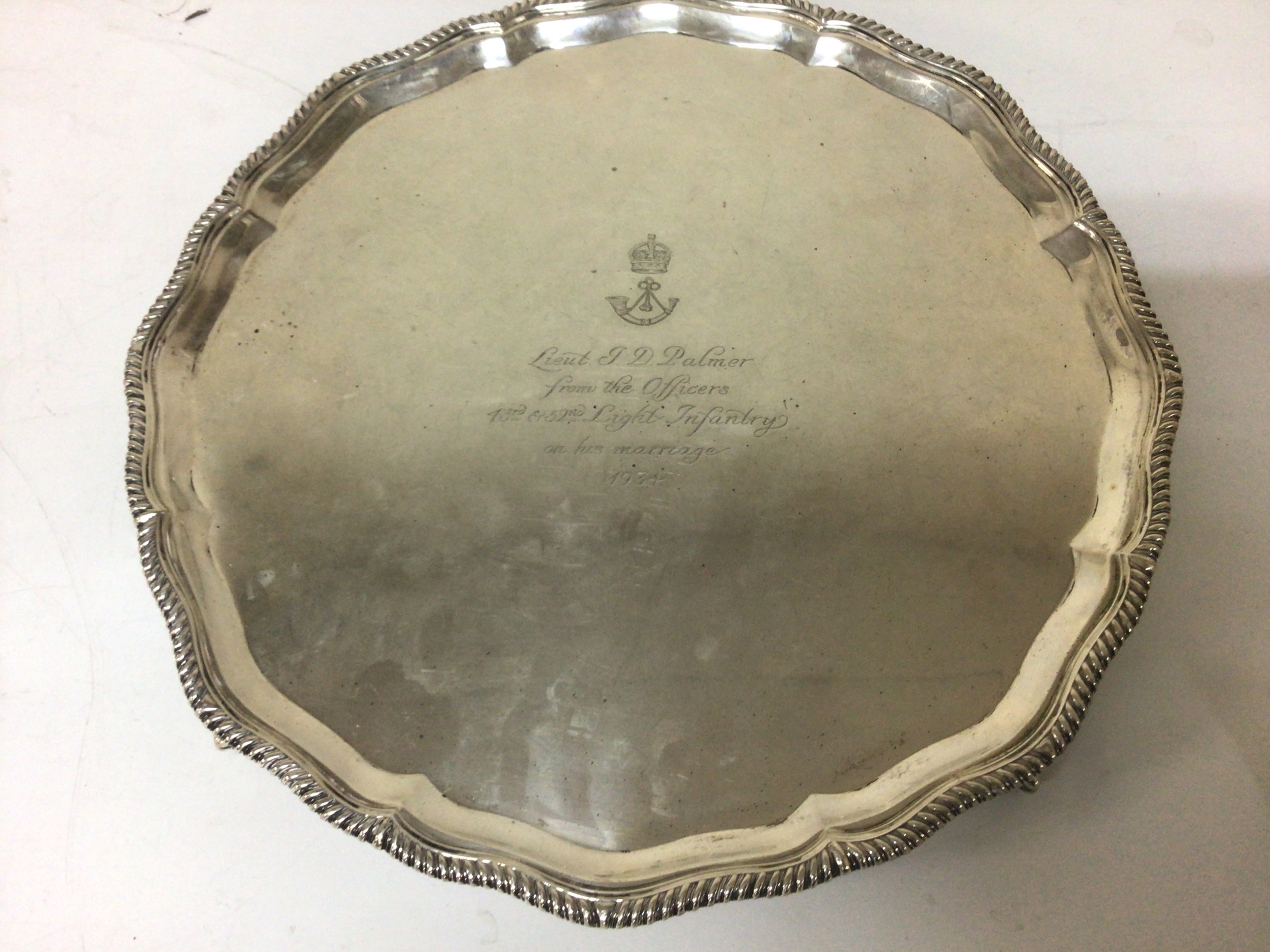A Silver tray with a shaped edge and ball and claw feet the tray with a personal Military inscription and date of 1934. Tray diameter 36cm weight 1260g approximately with Sheffield hallmarks.