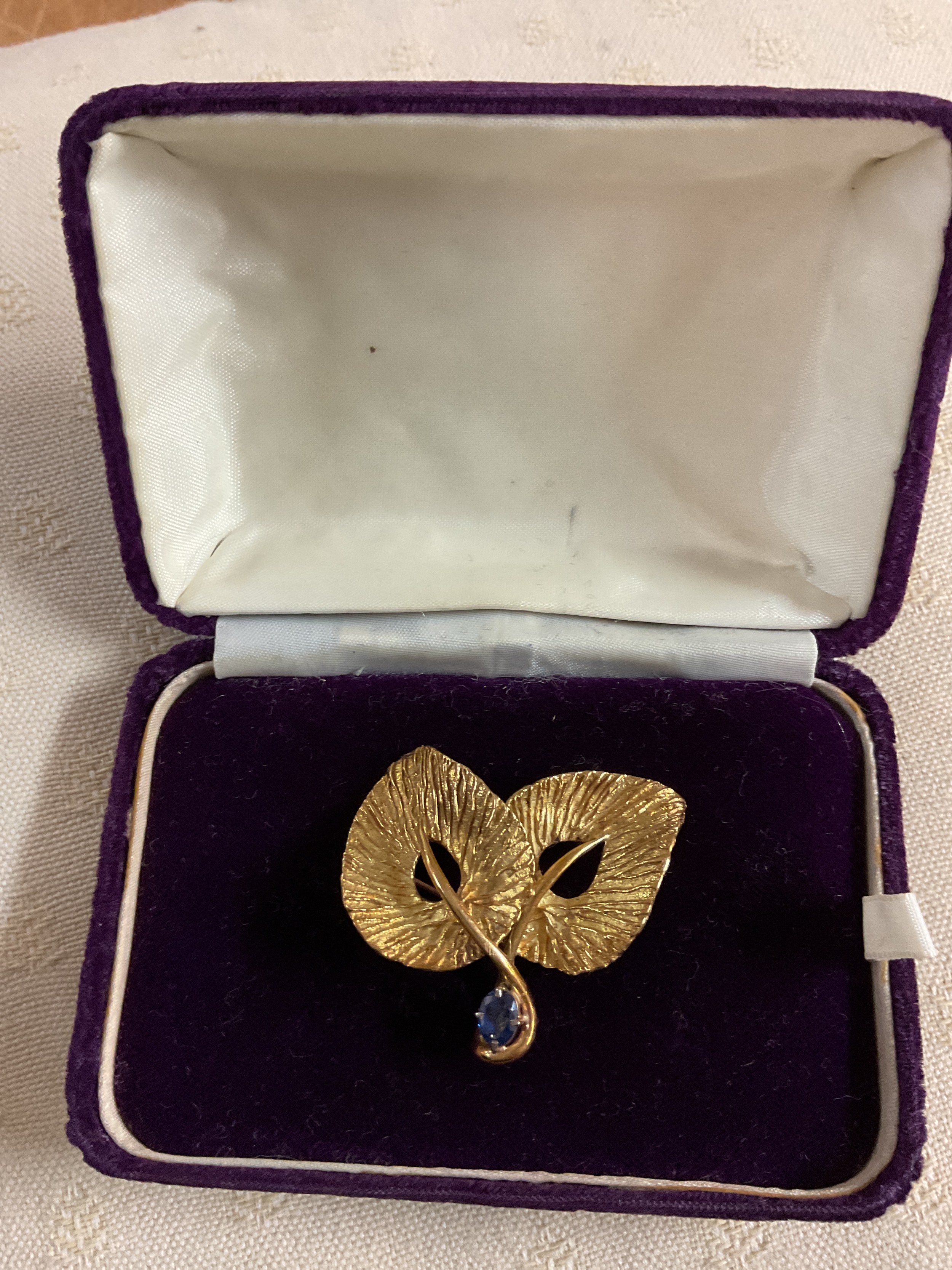 Cartier brooch, floral pattern of two leaves with a Sapphire set to the stem, signed to the back Cartier 18k. And hand engraved number 22300. Weight 13.5 grams.