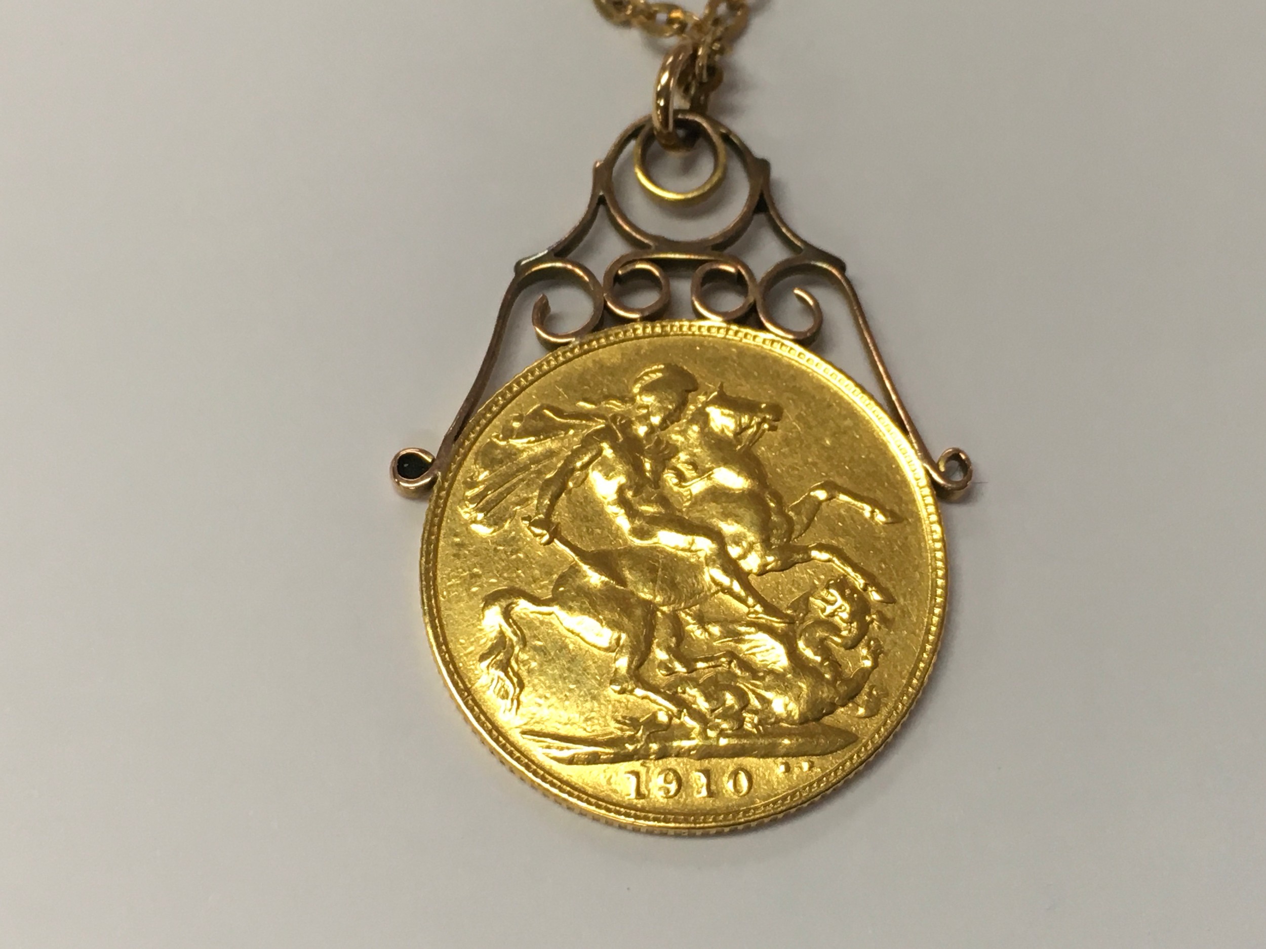 A full 1910 full sovereign with a soldered mount with 9ct gold chain. 11.40g