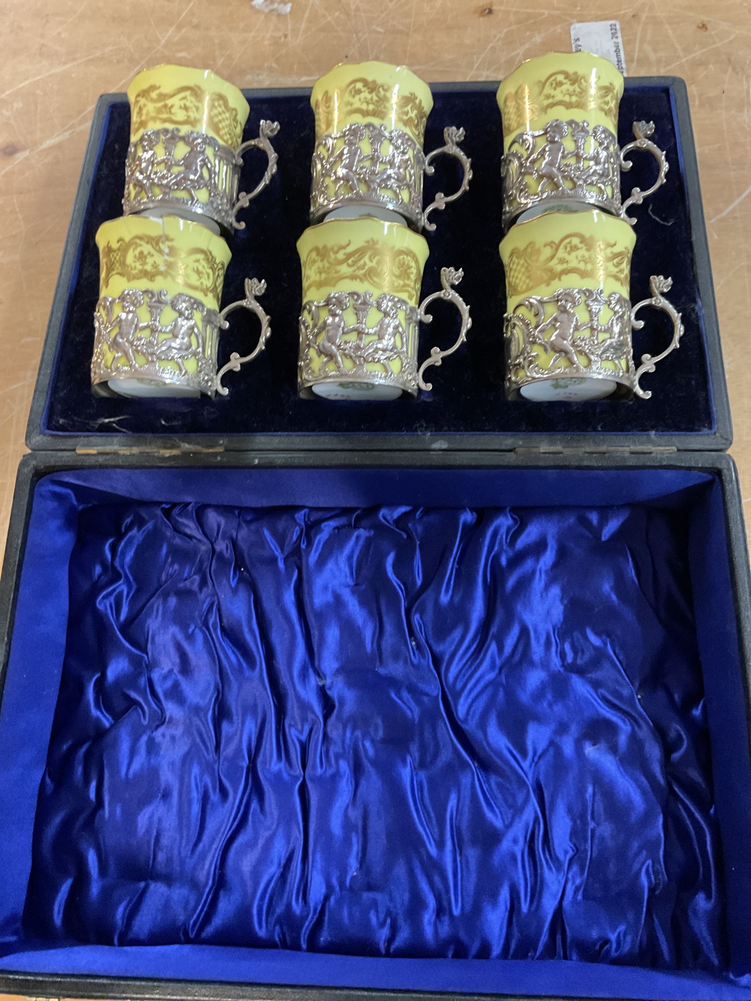Royal Worcester cased set of six coffee cans with silver holders, c1902 with silver hallmarks for London 1901 by William Hutton and Sons, one can is repaired, weight 150 grams.
