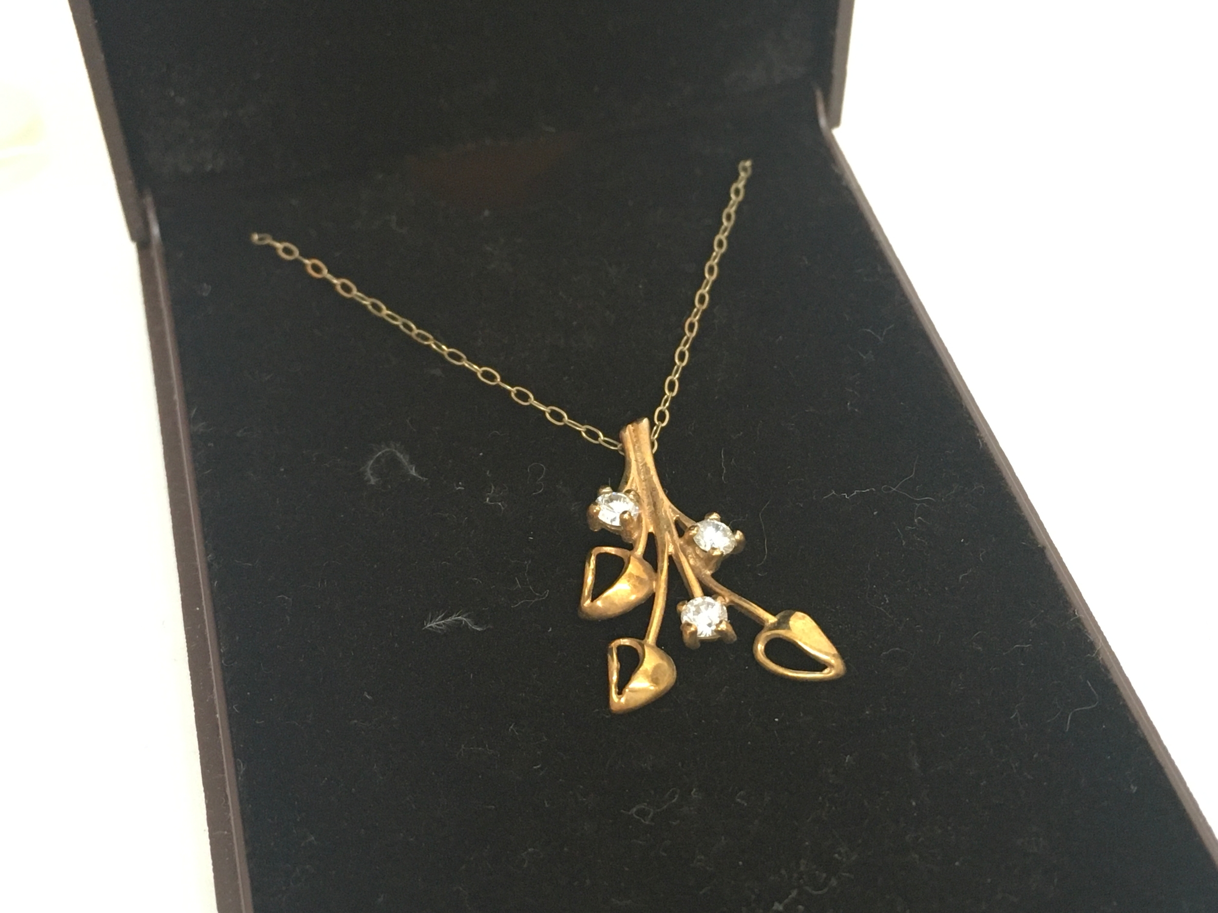 A 9ct gold pendant with three diamonds on a 9ct gold chain, 1.5g total weight. Necklace 21cm long
