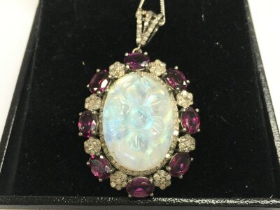 Silver pendant with carved opal on a floral design with garnet and diamonds on silver chain.