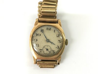 A 9ct gold cased vintage watch with a metal strap. Winds and runs.