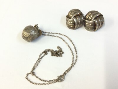 A pair of silver knot earrings and a silver apple pendant on chain