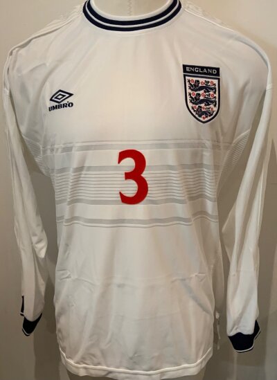 1999 England Gary Neville Match Worn Football Shirt: White home long sleeve Umbro number 3 shirt. Worn by Neville v Scotland on 17 9 1999. COA signed by player and photo from the press of him wearing it.