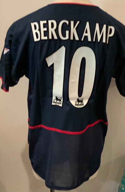 Arsenal Bergkamp Match Worn Football Shirt: Blue away short sleeve Nike 02 number 10 shirt with Bergkamp to rear. Premier League Champions 2001 - 2002 badging to one arms. Worn by Bergkamp v West Ham on 24 8 2002. COA signed by player. Inner mesh cut out but still evident.