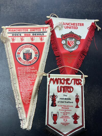 Manchester United Pennant + Rosette Collection: Late 60s pennant with old badge and 1960s honours, large pennant produced in 1976 and a smaller pennant from the late 70s all different. C/W 6 rosettes which are 1977 FA Cup final, 2 different 1983 FA Cup final and 3 more. Good. (9)