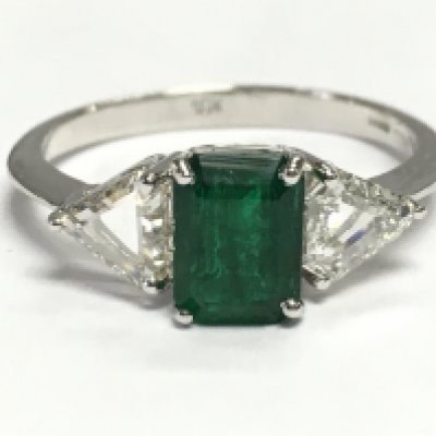 18ct white gold ring set with a rectangular step-cut emerald flanked by trilliant-cut diamonds. Emerald 1.18ct. Diamonds 0.60ct. Size O. 