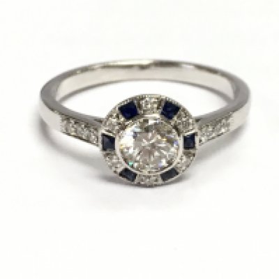 An 18ct white gold target style ring set with a central RBC diamond surrounded by square sapphires and further RBC diamonds, with diamond set shoulders. Diamonds 0.65ct sapphire 0.10ct. Size M/N. 3g total weight.