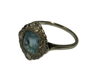 A 1930s platinum ring set with a central aquamarine surrounded by old cut diamonds. Size O.