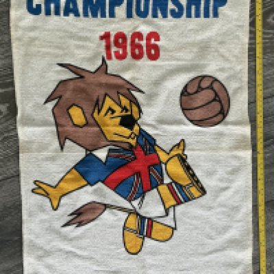1966 World Cup Willie Hand Towel: World Cup Willie printed underneath Willie with vibrant colours to middle kicking a football. The top reads World Cup Championship 1966. Probably too big for a tea towel so at 30 inches probably a hand towel. FA copyright to bottom. 