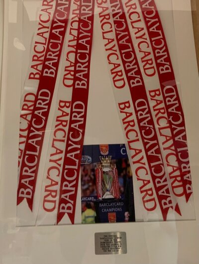 Arsenal Invincibles Premiership League Trophy Framed Ribbon: Official Barclaycard ribbon used on the Premier League trophy from Arsenals Invincibles 2003/2004 Championship winning players. Framed with picture of the ribbon on the trophy. Measures 63 x 94cm.