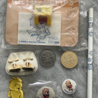 1966 World Cup Willie Football Memorabilia: Pair of cufflinks still attached to Football Association backing, gold and matching silver coin, yellow badge and two different size white ones, pencil and a sealed packet which states Willie Clips and has a plastic clip to attach paper. All 8 items feature World Cup Willie. 