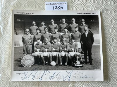 Manchester United 64/65 League Champions Signed Photo: Large black and white photo of the team and manager with the league championship trophy and charity shield to front. Hand signed to border by 13. Signatures include Law Dunne Gaskell Connelly Foulkes Stiles Brennan Best Charlton Crerand and Cantwell.
