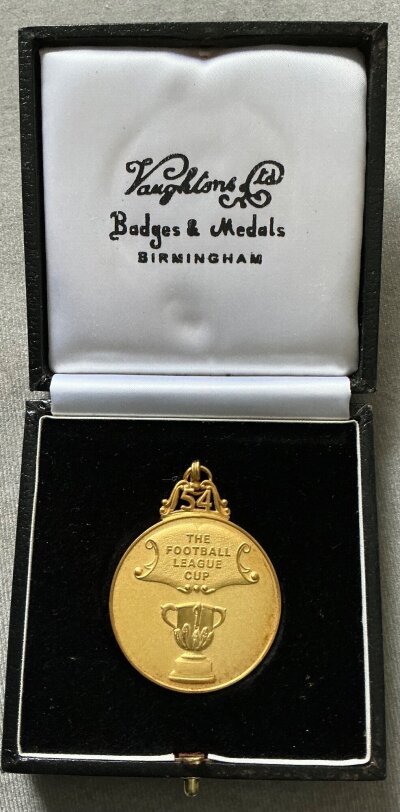 2014 Manchester City League Cup Winners Football Medal: Gold medal with ring suspension. The number 54 which indicates the 54th year of the League Cup and the words The Football League Cup. The reverse has an image of Wembley below the words Winners 2013-14. Medal is hallmarked and made by famous maker Vaughtons and comes with original box. Comes from Manchester City staff member.