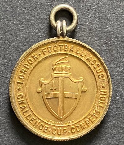 West Ham John Lyall London Challenge Cup Football Medal:: Awarded to John Lyall when West Ham finished runners up to Arsenal in the 1957 final. Quality silver gilt medal in original Vaughtons + Sons box.