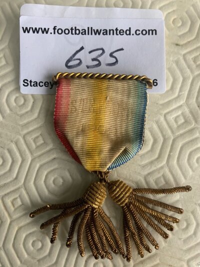 1909 Football Stewards Badge: Pink blue white and yellow cloth pin badge with words Steward 1909 fading. It is not clear if this is a stewards badge for an England International or the Manchester United v Bristol City FA Cup Final as it is not evident from item.