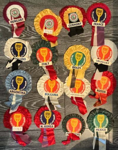 1966 World Cup Complete Football Rosettes: All 16 participating nations included. Purchased by vendor over the competition at Wembley during the World Cup. Excellent condition with 13 not only having the team but the Jules Rimet trophy and words World Cup 1966. Hungary Spain and West Germany state International Football. Rare chance. (16)