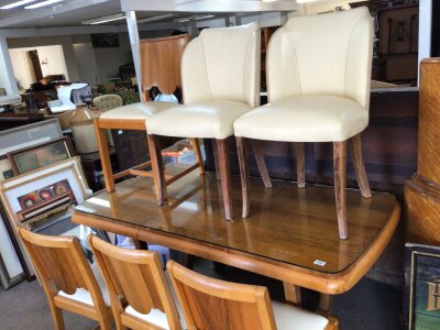 An Art Deco Design mid 20th Century Walnut  dining table and chairs including a pair of leather upholstered chairs table and a set of four chairs the table with extra leaf and shaped supports.