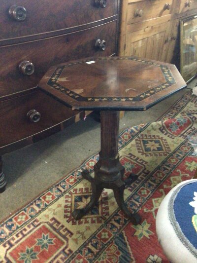 A late Regency occasional table in the style of George Bullock, the octagonal top inlaid with a band of foliage on a conforming column and splayed legs.