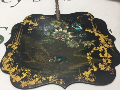 A Victorian paper mache fan (24cm wide) with decoration of flowers and peacock, and wooden handle.