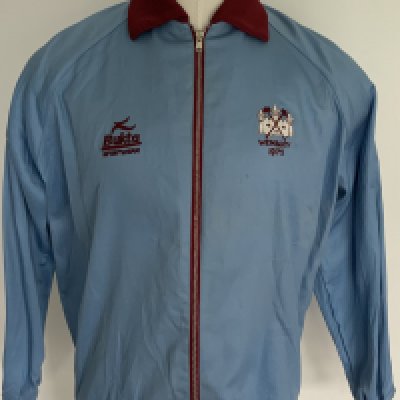 West Ham 1975 FA Cup Final Tracksuit Top: Stunning light blue with claret trim zip up track suit top. Bukta Sportswear to breast and label with Wembley 1975 underneath West Ham embroidered badge to other breast. Worn on the historic cup final winning day by double goalscorer Alan Taylor who has provided a COA. Going under the hammer only 4 days before the 50th anniversary of this match v Fulham.