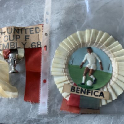 1968 European Cup Final Football Rosettes: Rare Manchester United rosettes with plastic cup hanging from red and white ribbons. C/W Benfica rosette with plastic player in white kit. Nice items. (2)