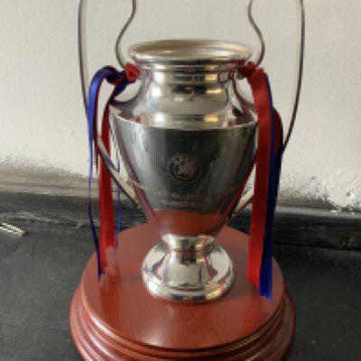 Champions League Replica Trophy: Small trophy with what could be Barcelona ribbons attached. Wooden plinth that it sits on could be original. Approximately 7 inches high.