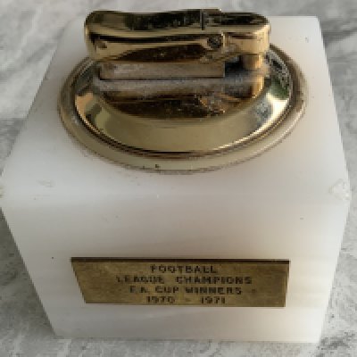 Arsenal Double Team 70/71 Football Lighter: Heavy marble lighter with one side stating Football League Champions FA Cup Winners 1970 - 1971. Reverse has an enamel badge of Arsenal. Lighter produced by Calibri is not in working order. Presented by the club.