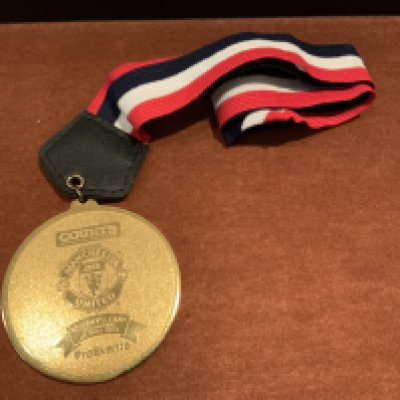 2001 Singapore X1 v Manchester United Players Medal: Large gold coloured medal with Manchester United badge and the words Courts Cup Singapore 24 7 2001. The reverse has the words Champions. Red white and black lanyard attached. Awarded to a Manchester United player.
