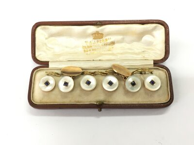 A boxed set of unmarked gold, mother of pearl and sapphire cufflinks and collar studs.